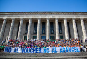 Estudiantes en la Facultad de Derecho de la UBA sostienen un cartel con la leyenda "No al voucher, no al arancel".